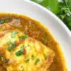 piece of fish in curry in a white bowl