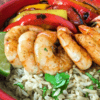 red bowl with cilantro rice, shrimp and fajitas peppers and onions
