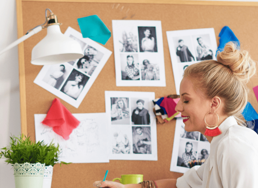 woman sitting in front of cork board with pictures and cloth pinned on it