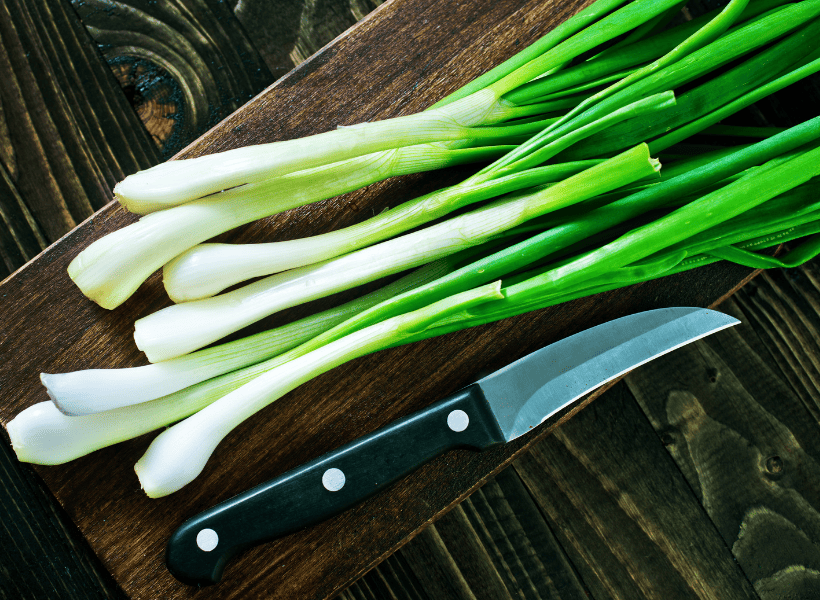 green onions on cutting board beside knife