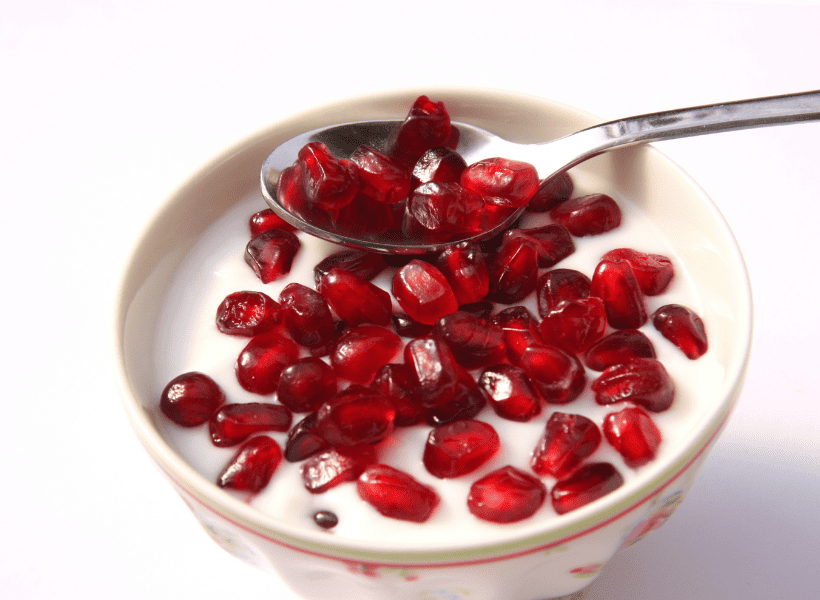 pomegranates in a bowl of yogurt with a spoon