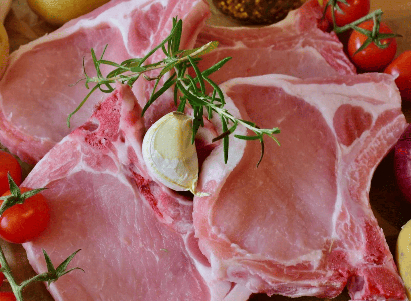 plate of raw pork chops with butter and seasoning