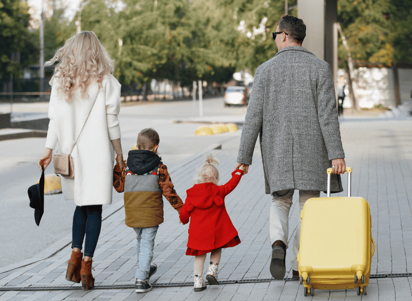 family of 4 walking away with suitcases