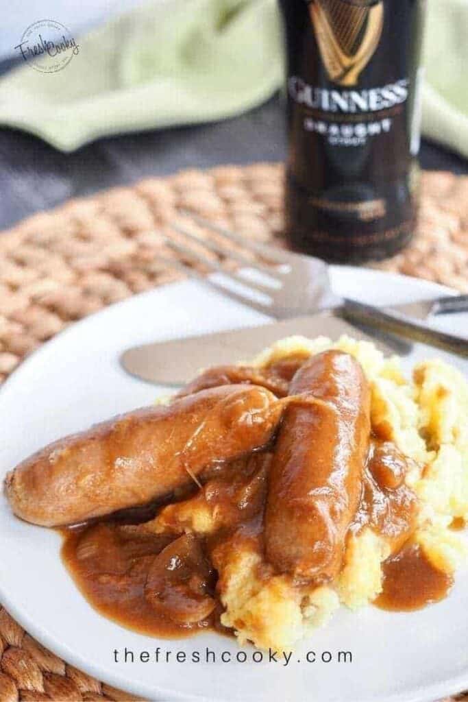 white plate of bangers and mash with milk stout gravy on top