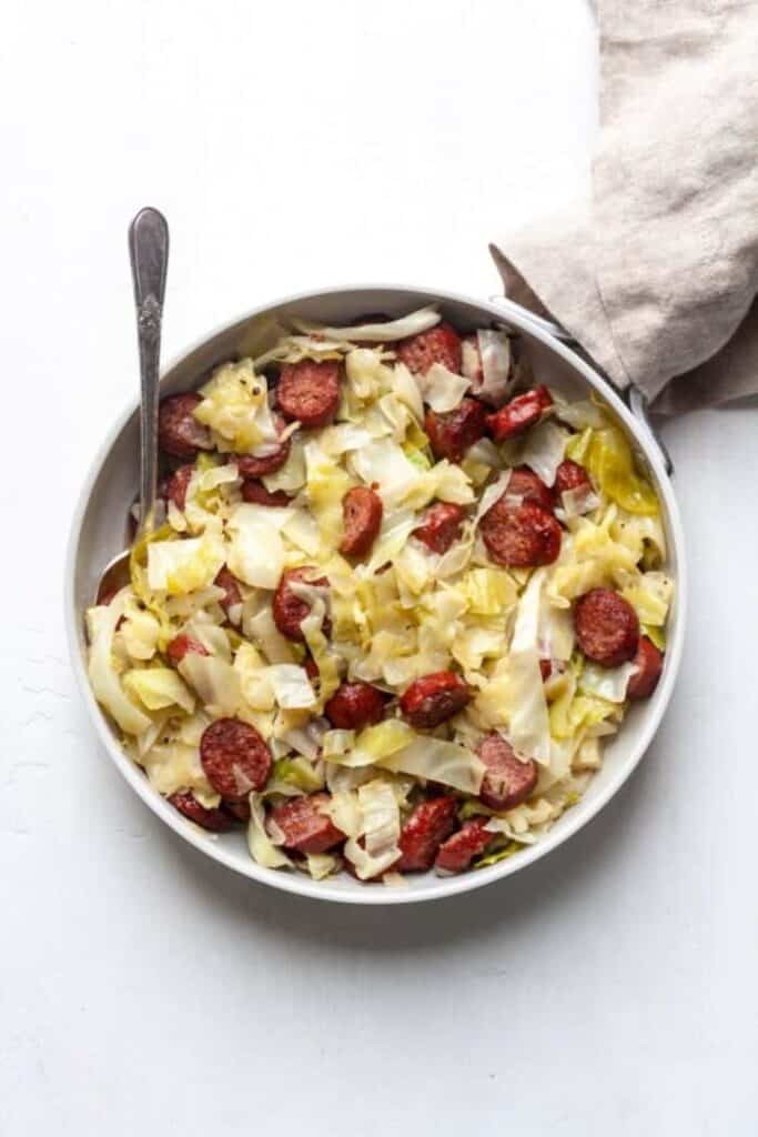 paleo braised cabbage and sausage in a white serving dish