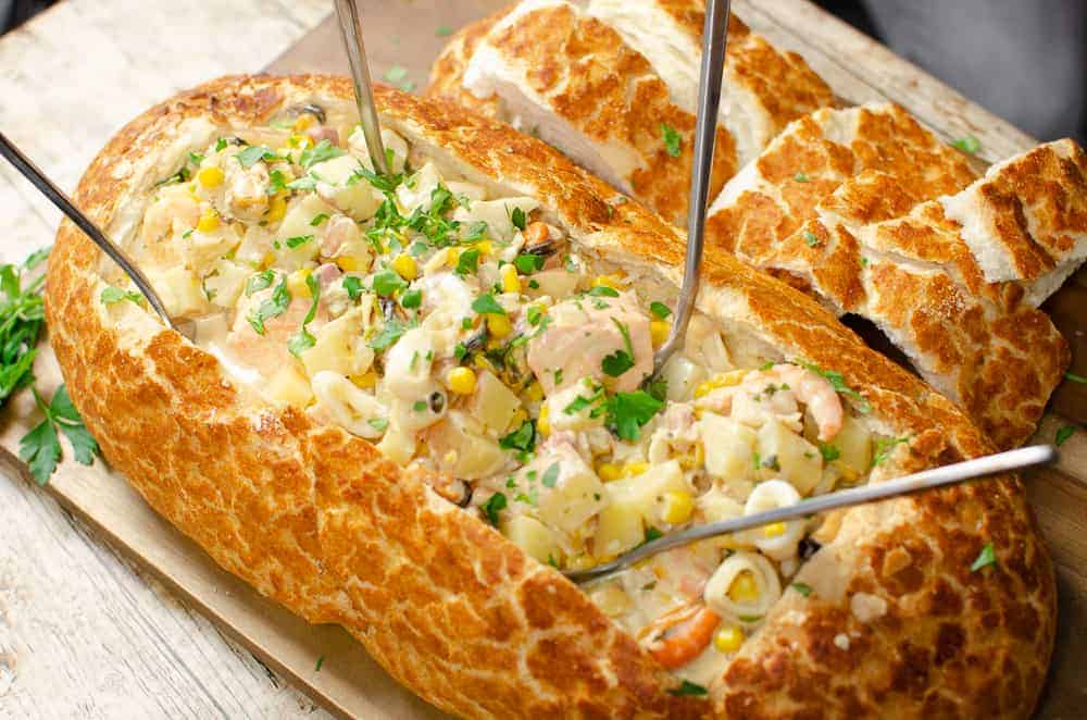 fish chowder in a large bread boat with forks 