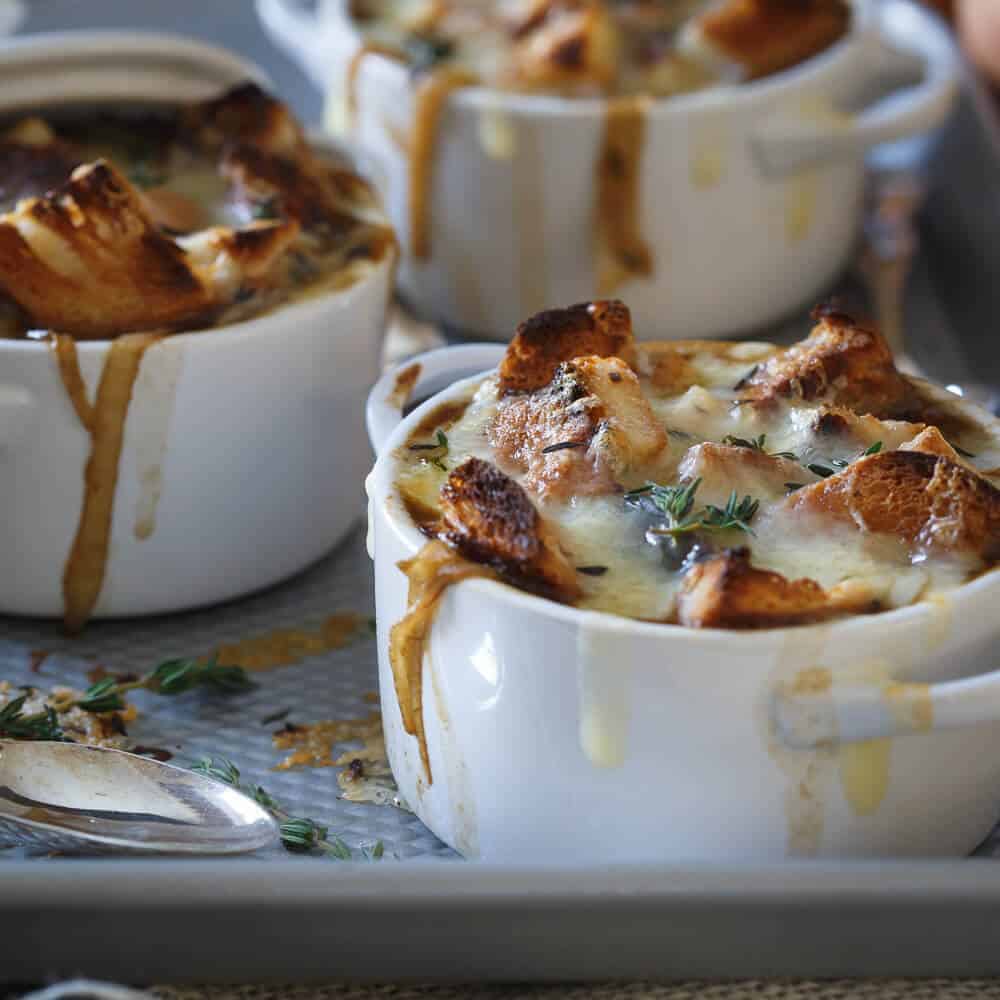 irish stout onion soup in white individual bowls with cheese and bread cubes toasted