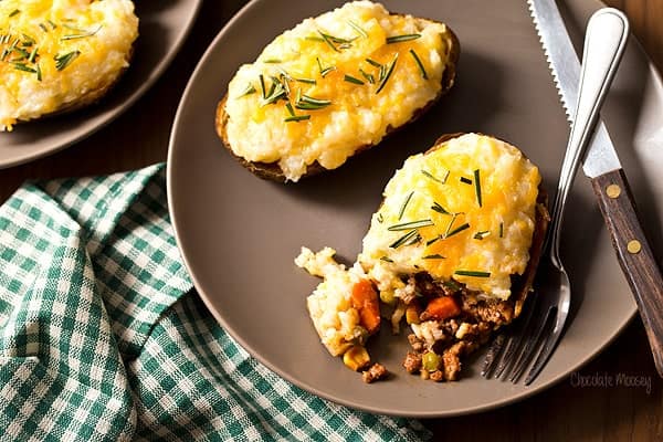 twice baked potato shepherd's pie on a brown plate with fork and knife