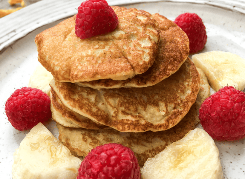 stack of coconut flour pancakes with bananas and raspberries on plate