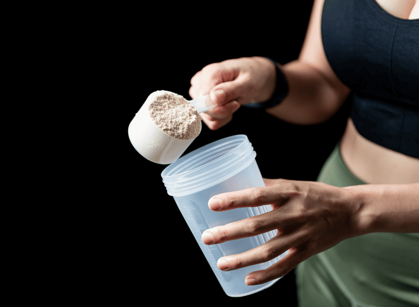woman holding bottle putting scoop of protein in
