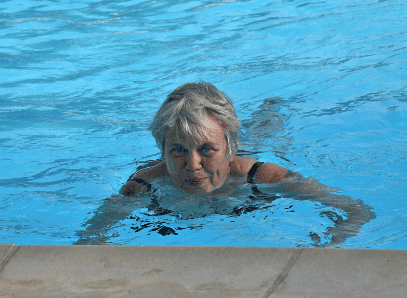 senior woman swimming in pool looking at camera