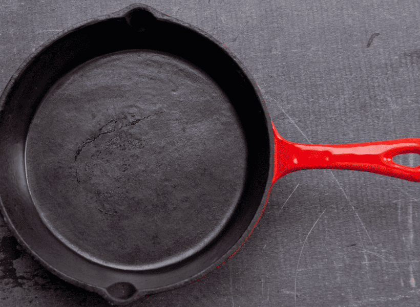 cast iron frying pan with red handle