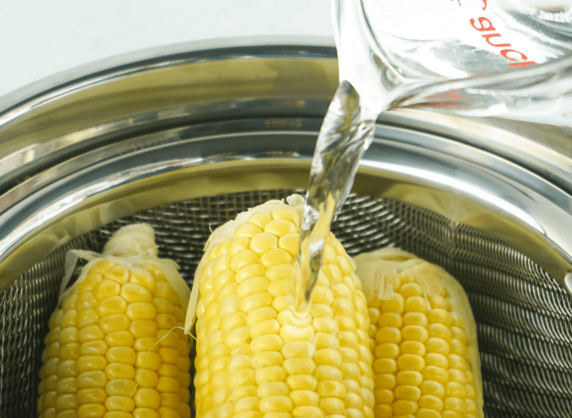 corn on cob in instant pot and water being poured in