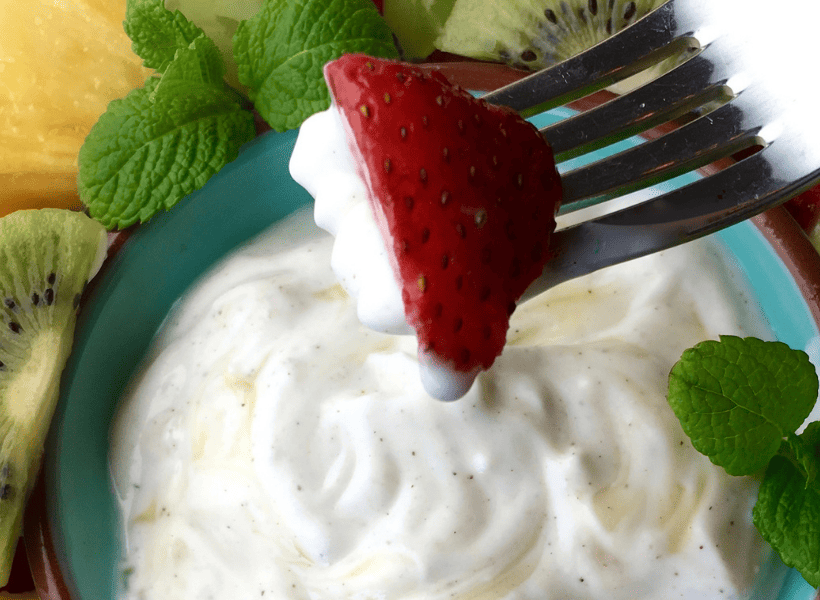 yogurt dip with a strawberry on a fork dipping into it