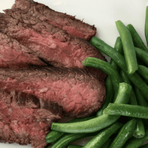tri tip steak medium rare with green beans on white plate
