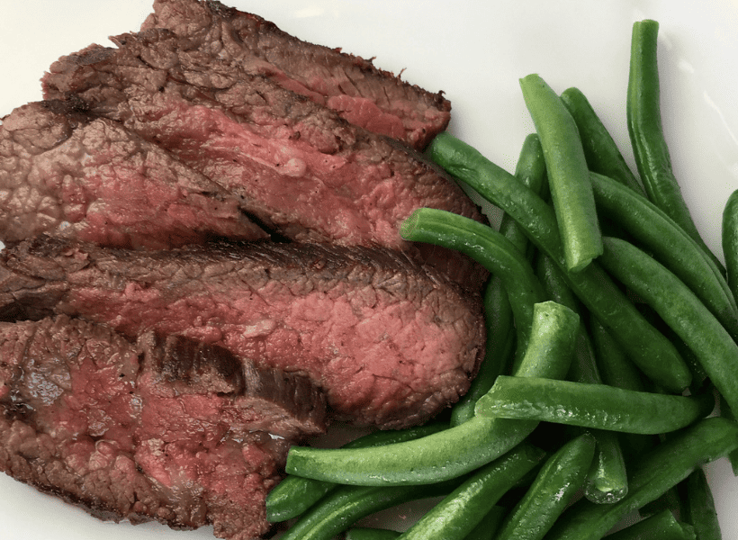 tri tip steak medium rare with green beans on white plate