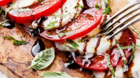 caprese salad on cutting board with fork