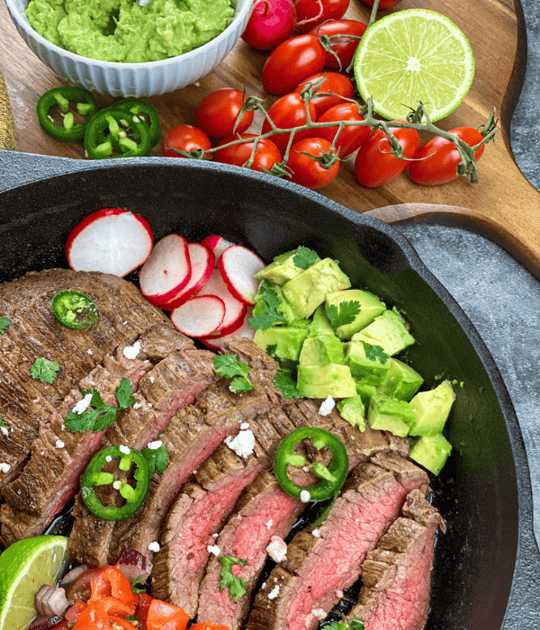 carne asada in cast iron skillet with fixings