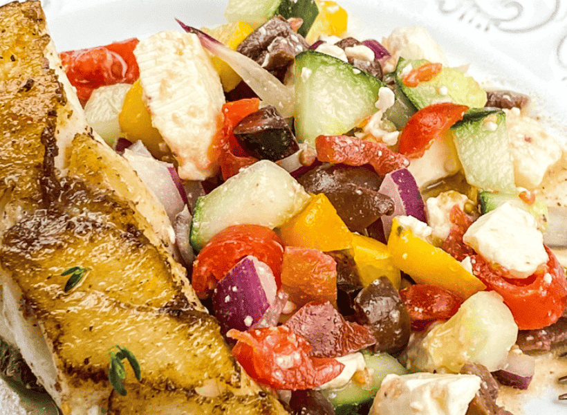 pan seared mahi mahi on plate with tomato cucumber kalamata olives salad