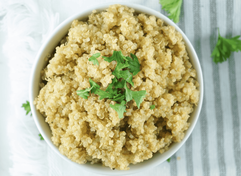 white bowl of cooked quinoa with parsley on top