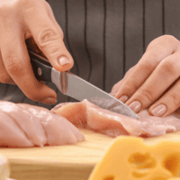 raw chicken breast on cutting board being sliced