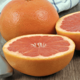 pink grapefruit cut in half beside whole grapefruit