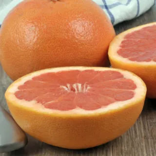 pink grapefruit cut in half beside whole grapefruit