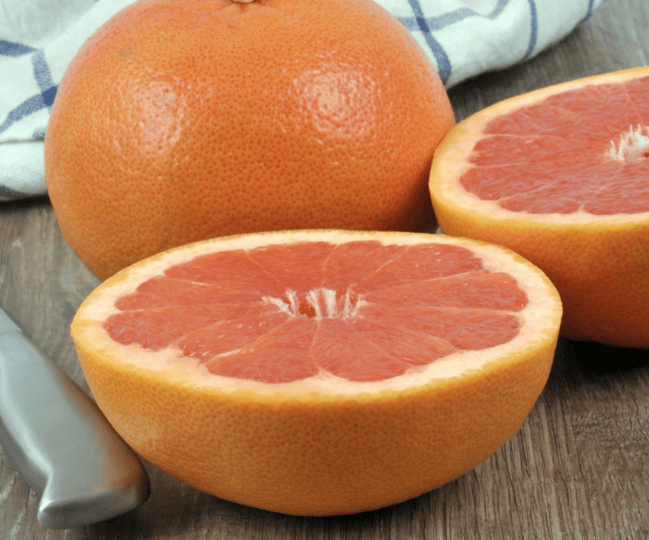 pink grapefruit cut in half beside whole grapefruit