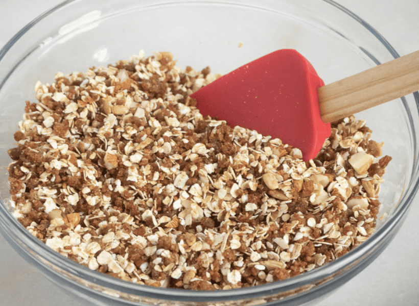all ingredients for homemade granola being mixed in glass bowl