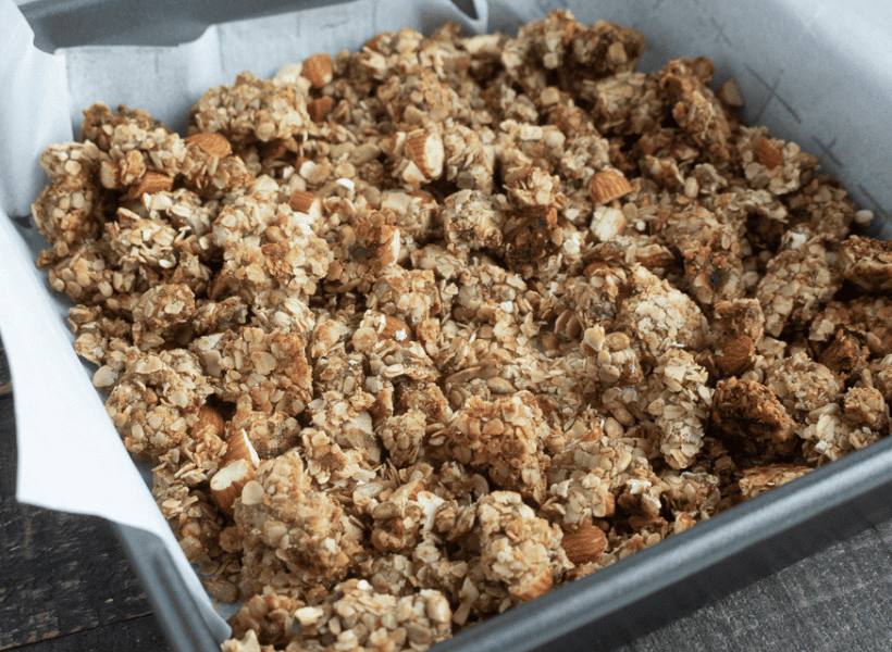 baked homemade granola in pan with parchment paper around it