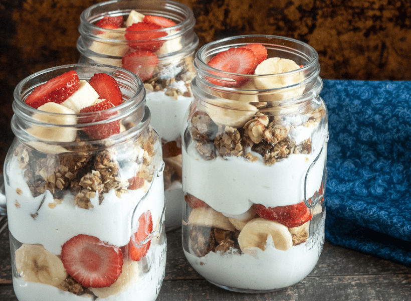 homemade granola layered with strawberries and bananas in glass jars