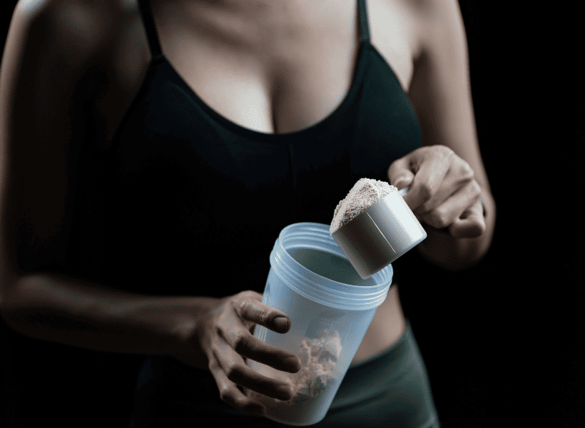 woman putting scoop of powder in shaker bottle