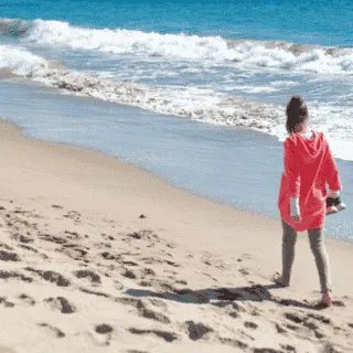 lady walking on beach holding shoes