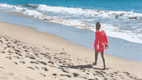 lady walking on beach holding shoes