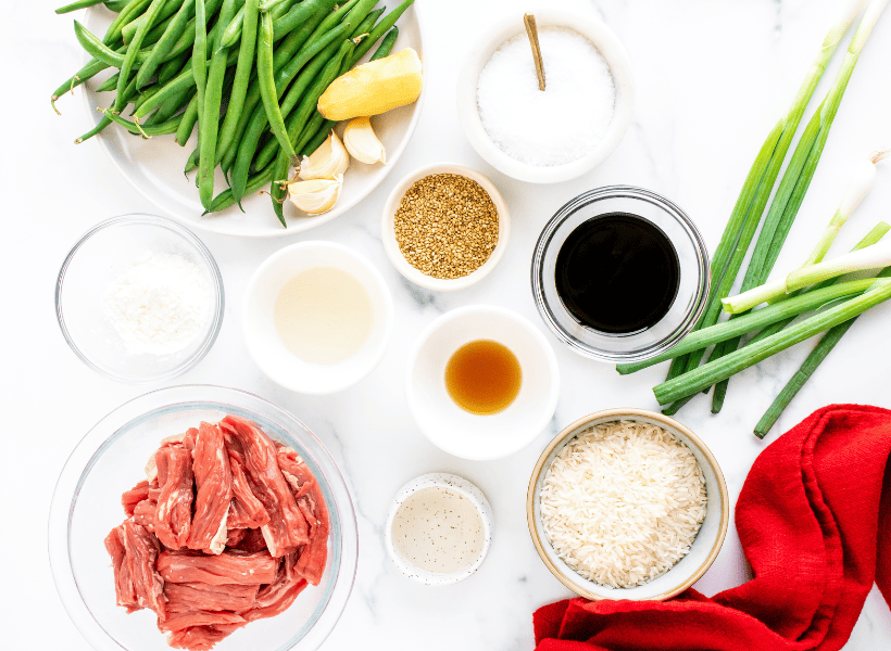 ingredients for beef and green beans in bowls on white counter
