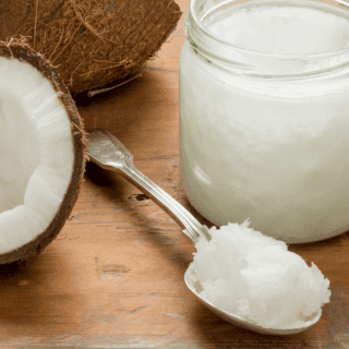 coconut split open on counter beside glass container of coconut oil