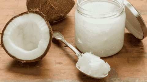 coconut split open on counter beside glass container of coconut oil