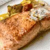 salmon with herb butter on a plate with vegetables