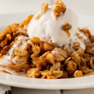 white bowl of apple crisp with vanilla ice cream on top