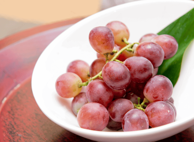 small group of red grapes on white plate