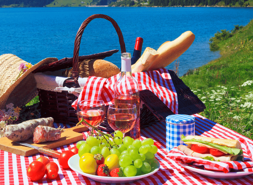 grapes and other food on picnic blanket by lake