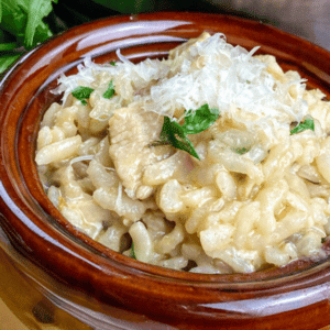 brown bowl of chicken risotto with grated parmesan on top