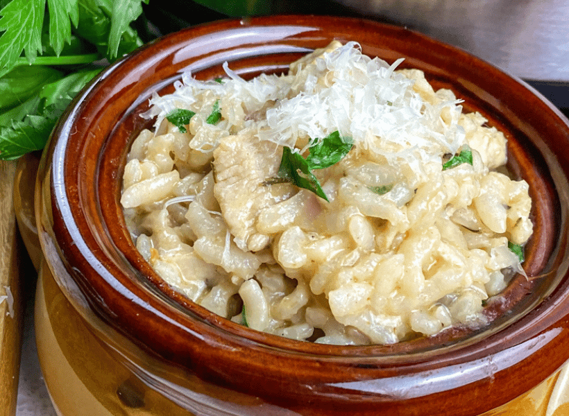 brown bowl of chicken risotto with grated parmesan on top
