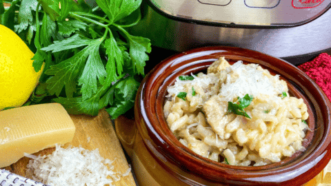 bowl of chicken risotto beside an Instant pot lemon and parsley