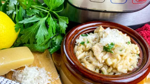 bowl of chicken risotto beside an Instant pot lemon and parsley