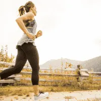 woman running outdoors by a wooden fence