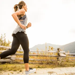 woman running outdoors by a wooden fence