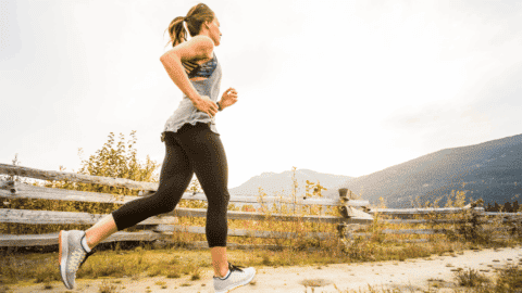 woman running outdoors by a wooden fence