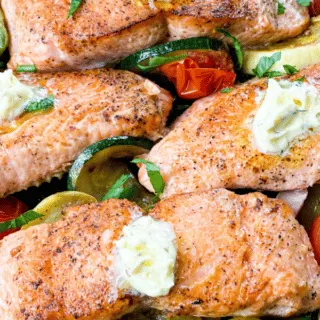 cooked salmon with vegetables in a cast iron skillet