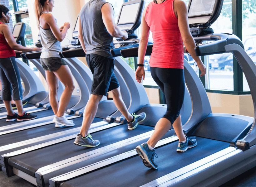 treadmills lined up in gym with people walking on incline